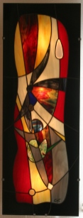 "Eyjafjöll" est une imposante et élégante applique murale en vitrail Tiffany (hauteur 96 cm, largeur 35 cm, épaisseur hors tout mur-panneau : 7,5 cm) suggérant l'explosion des matières