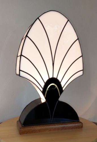 Lampe Art Déco en véritable vitrail Tiffany "Palmette 1919" Directement inspirée des vitraux de la Villa Laralde à Biarritz ayant appartenue à Gabrielle dite Coco Chanel (https://lumiere-et-vitrail.fr/galerie-huisseries/#jp-carousel-675) Verres opalescents Blanc pur et Noir laqué sur lequel un filet d'or 22K patiné y est incrusté par fusing. Pas moins de 4 cuissons de 18 heures sont nécessaires pour fabriquer cette lampe : les verres plats à l'origine sont soumis à une température de 680° afin de se courber sur des moules spécialement fabriqués sur mesure. Soudures patinées noires pour un aspect ancien Socle en chêne doré massif vieilli finition patine antiquaire gomme laque